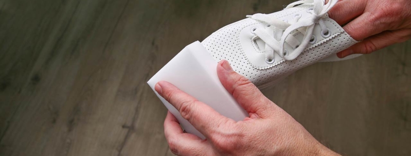 Photo of a man cleaning white sneakers with melamine sponge