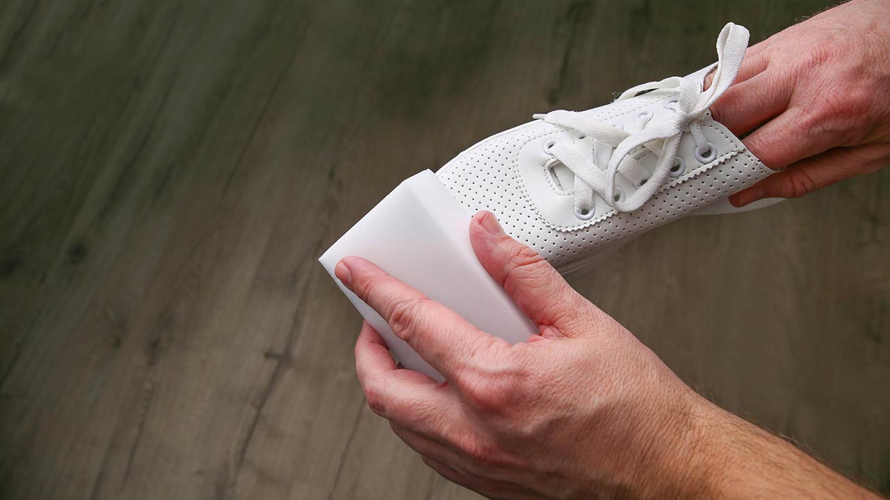 Photo of a man cleaning white sneakers with melamine sponge