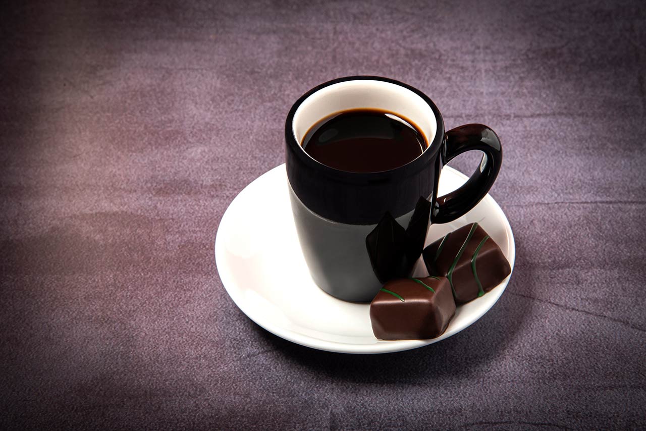 Photo of a cup of espresso with chocolate bonbons.