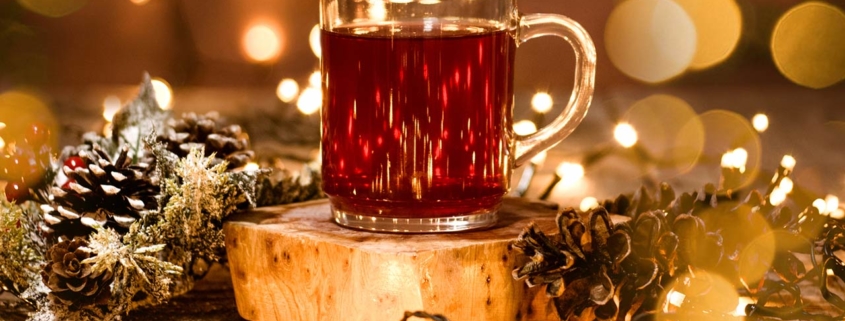 Photo of a holiday scene of a tea mug with decoration and bokeh lights on a wooden table and christmas lights