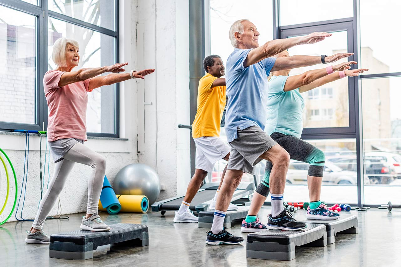 Photo of senior athletes synchronous exercising on step platforms at gym