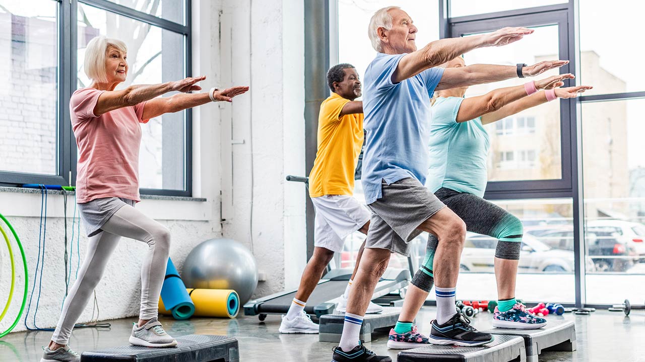 Photo of senior athletes synchronous exercising on step platforms at gym