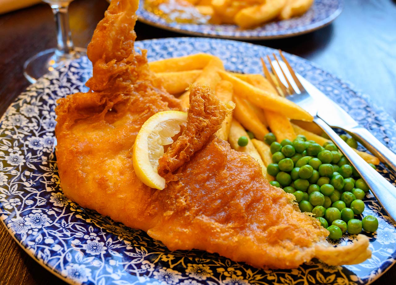 Photo of traditional British food fish and chips served with green peas in pub