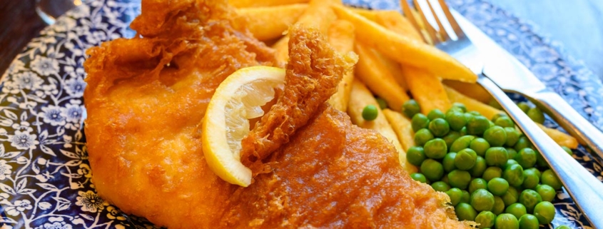 Photo of traditional British food fish and chips served with green peas in pub