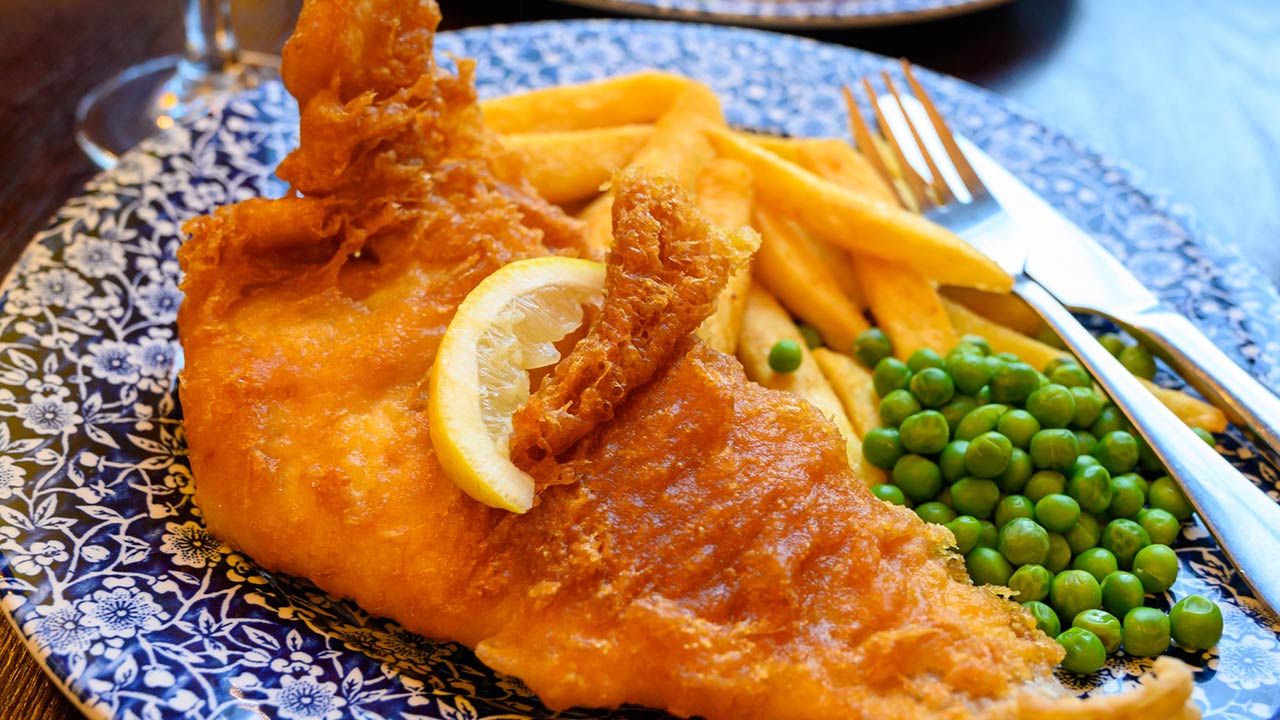 Photo of traditional British food fish and chips served with green peas in pub