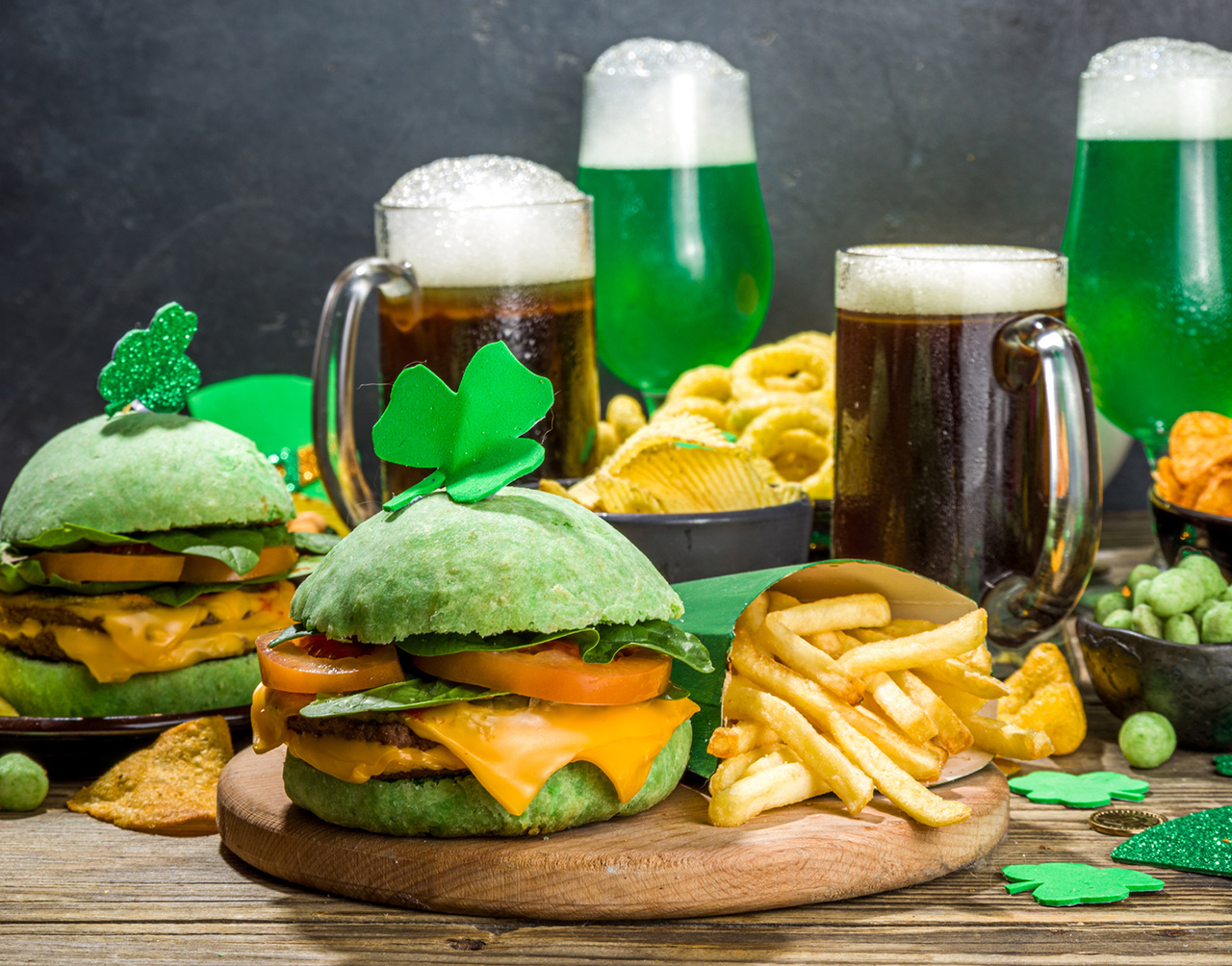 Irish St Patrick`s day beer, ale glasses, snacks, appetizer, green burger, wooden bar table with shamrock, clover, coins, leprechaun hat