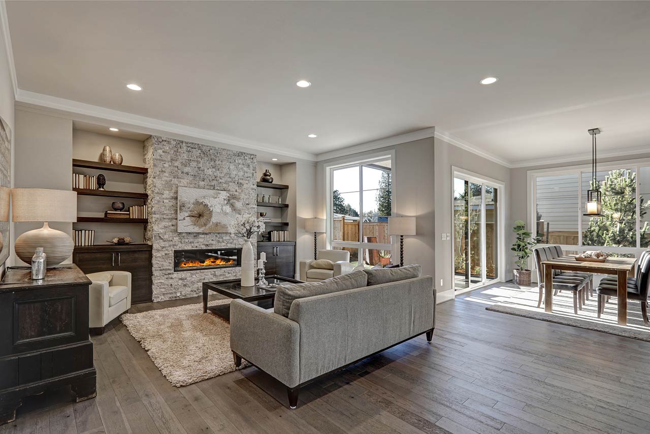 Living room interior in gray and brown colors features gray sofa atop dark hardwood floors facing stone fireplace with built in shelves Dean s Team