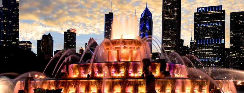 Water fountain with beautiful sunset and colorful light changes illuminating the Chicago skyline in the background
