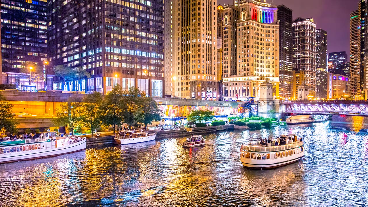 Beautiful downtown Chicago at night with lit buildings, river and bridge