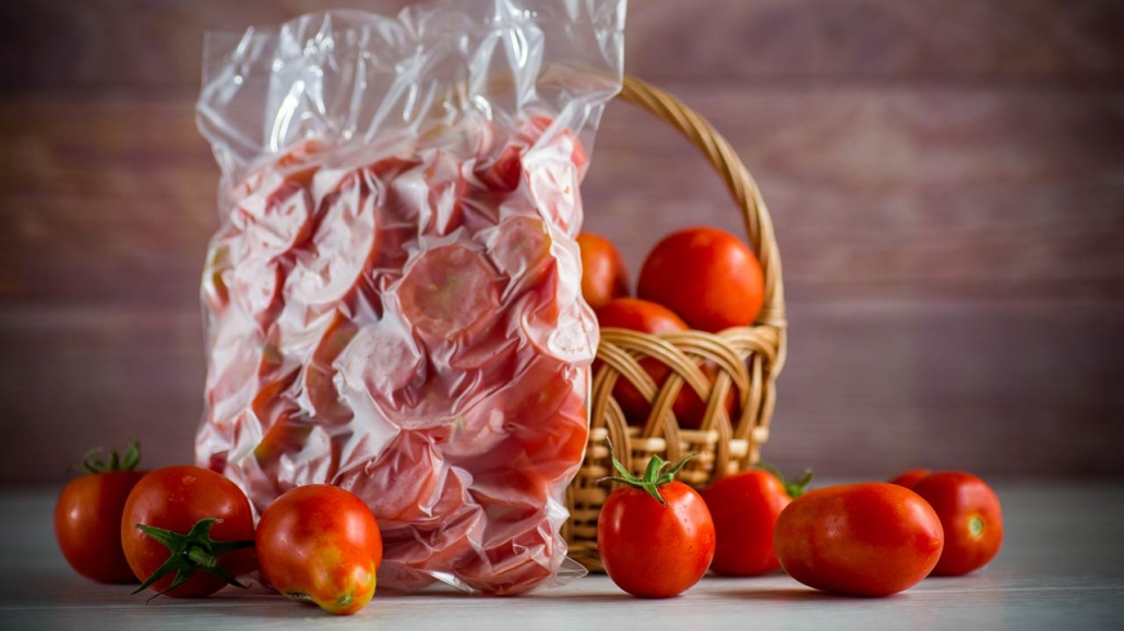 Frozen tomatoes in a vacuum bag on a wooden table
