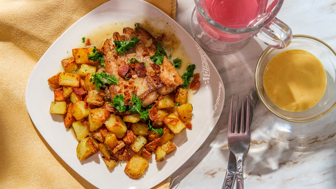 Tuscan salmon fillet in creamy butter garlic sauce with kale topped with crumbled bacon served over fried potatoes