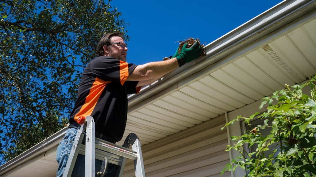 Worker cleaning gutters on a customers home