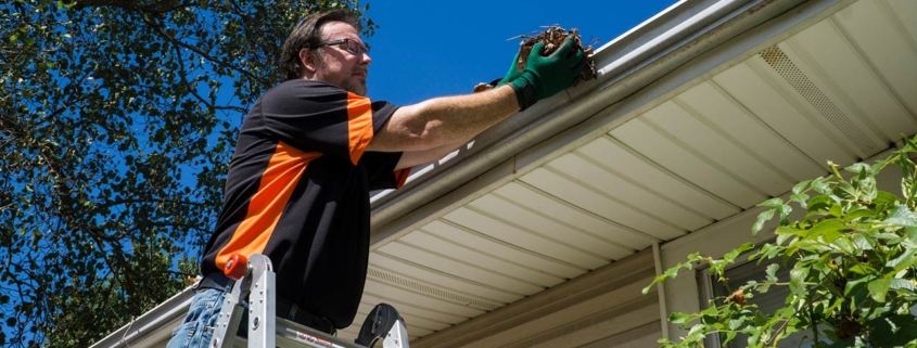 Worker cleaning gutters on a customers home