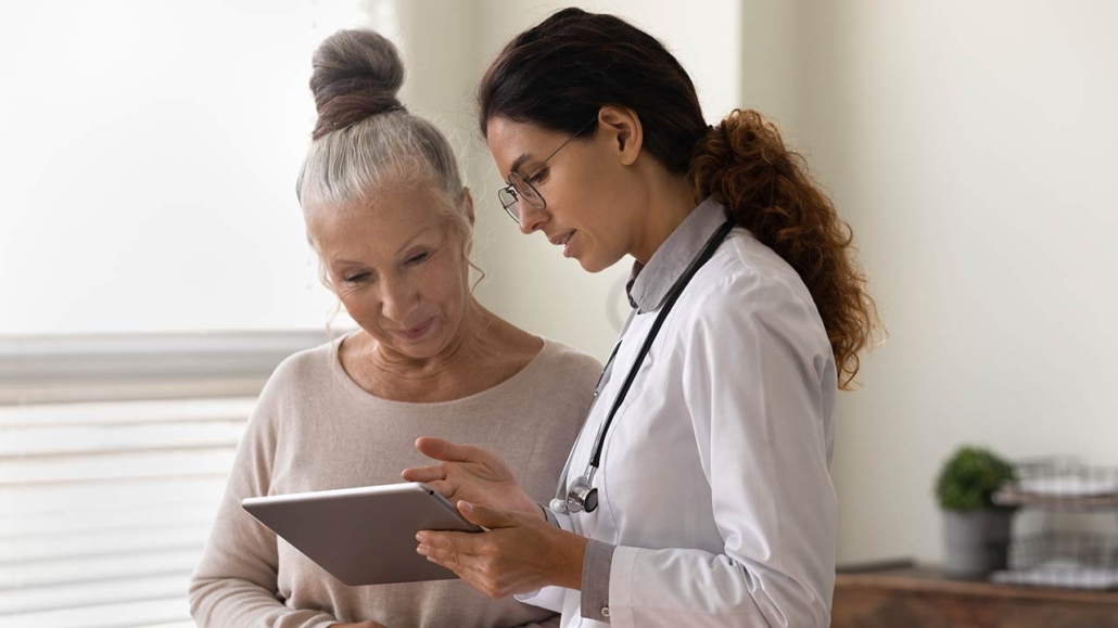 Doctor showing tablet screen to an older female patient