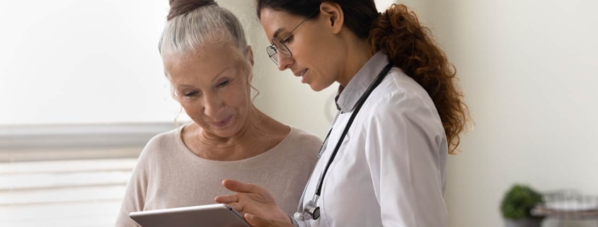 Doctor showing tablet screen to an older female patient