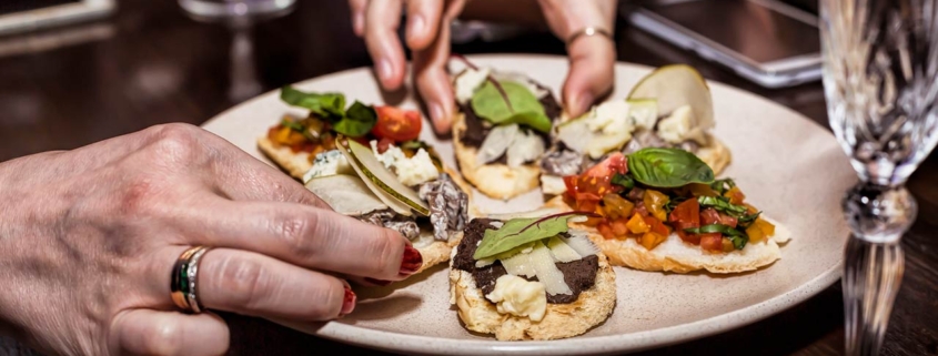 Two hands grabbing mini tacos off of a shared plate