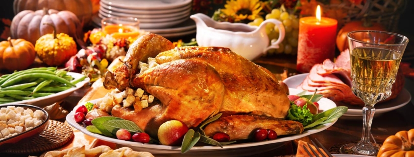 Roasted turkey garnished with cranberries on a rustic style table decoraded with pumpkins, vegetables, pie, flowers, and candles