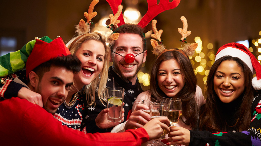Group Of Friends Enjoying Christmas Drinks In Bar Smiling To Camera