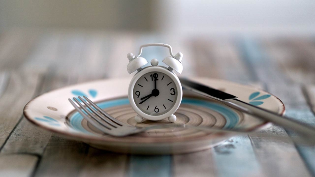 Close up view of alarm clock on a plate intermittent fasting diet concept