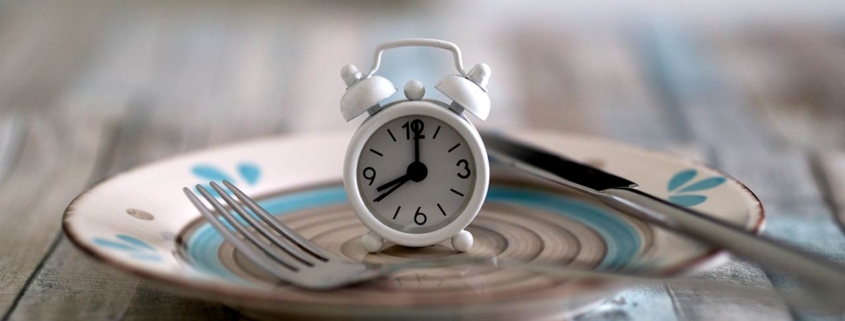 Close up view of alarm clock on a plate intermittent fasting diet concept