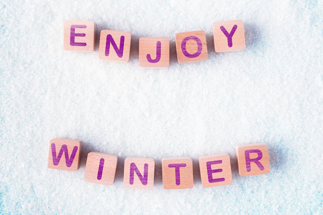 Wooden blocks and in snow with words Enjoy Winter