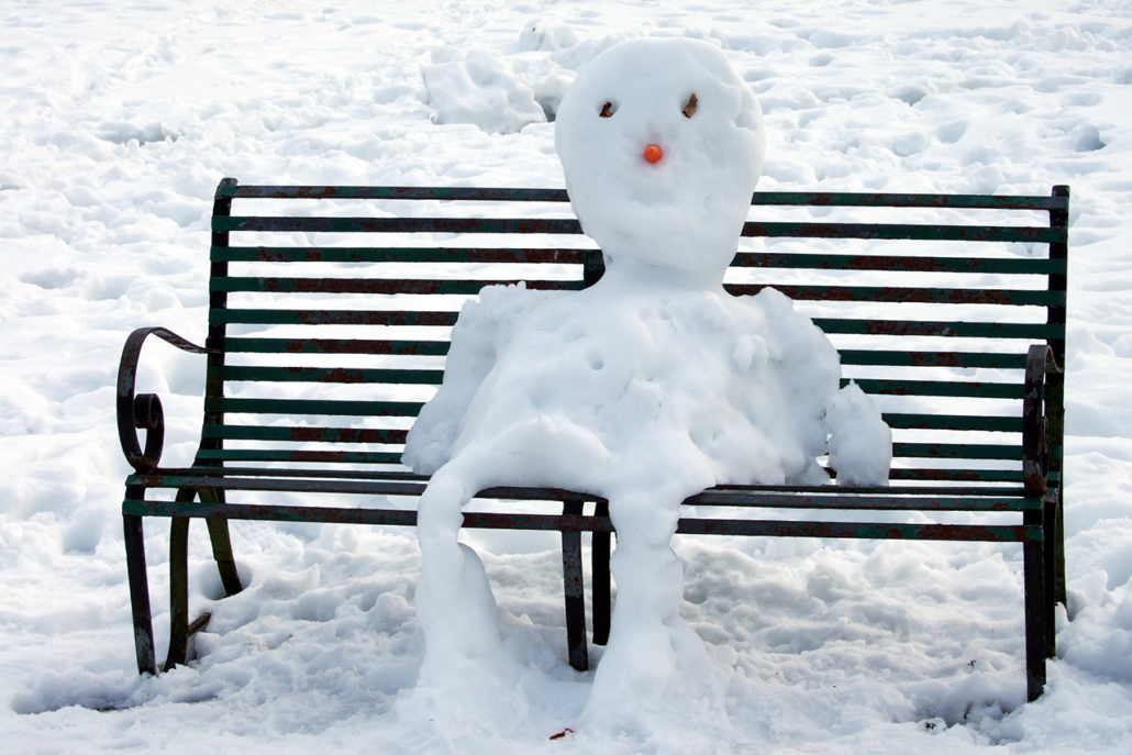 melting snowman sittingh on a park bench