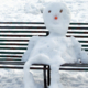 melting snowman sittingh on a park bench