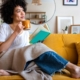 Relaxed African american woman reading a book at home, drinking coffee sitting on the couch
