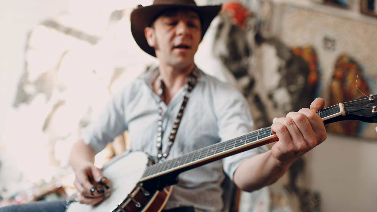 Male musician playing banjo sitting in a chair
