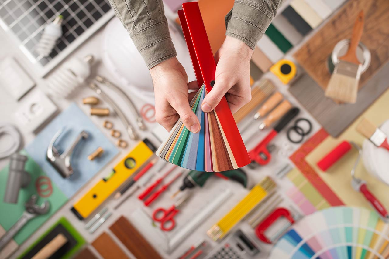 Male hands holding swatches and choosing the right color, work tools on background top view