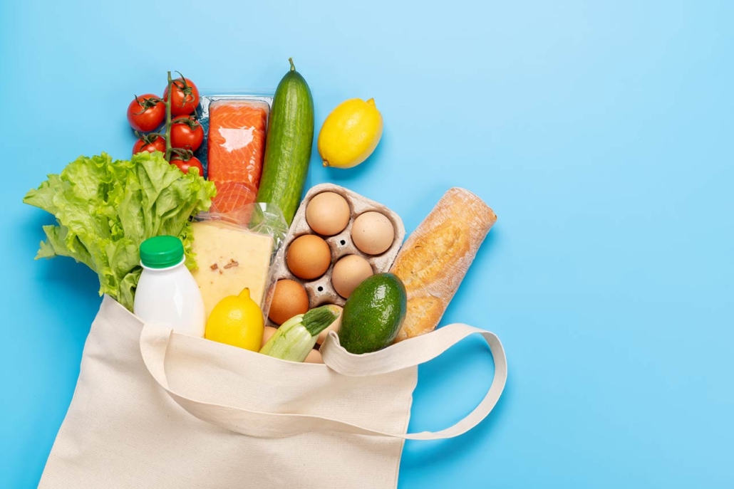shopping bag full of healthy food on blue background