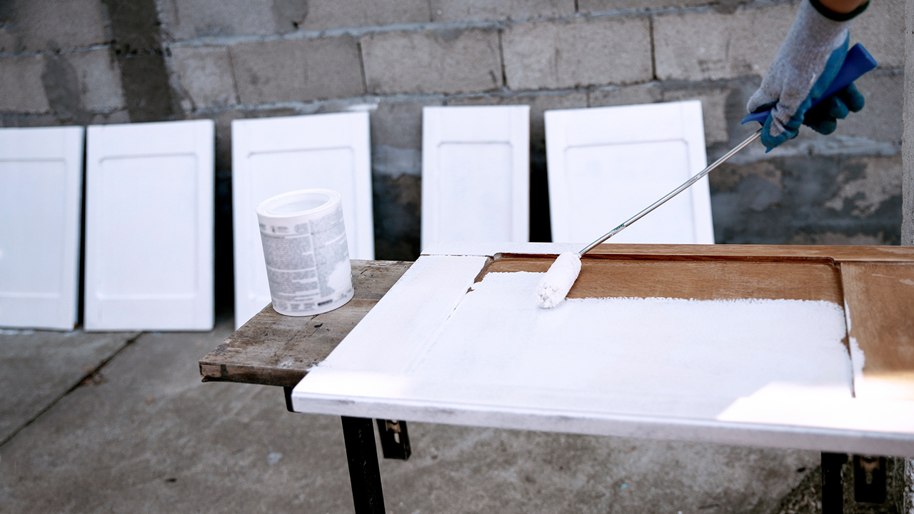 Painting old kitchen cabinets in white using a roller