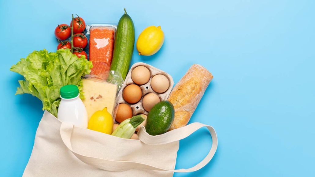 shopping bag full of healthy food on blue background
