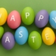 colorful painted eggs with happy easter letters on green background