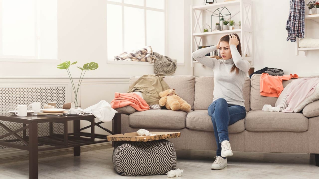 desperate helpless woman sitting on sofa in messy living room
