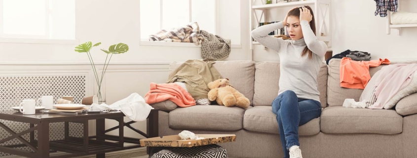 desperate helpless woman sitting on sofa in messy living room
