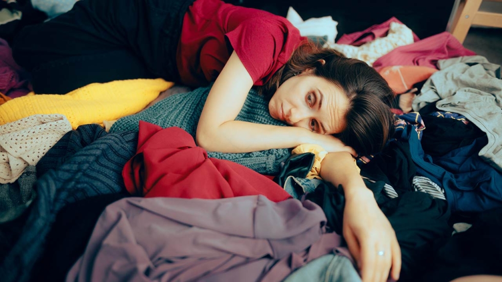 stressed woman having to fold and arrange all her wardrobe