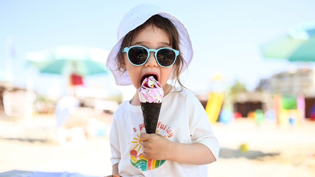 a child eating ice cream cone on the beach