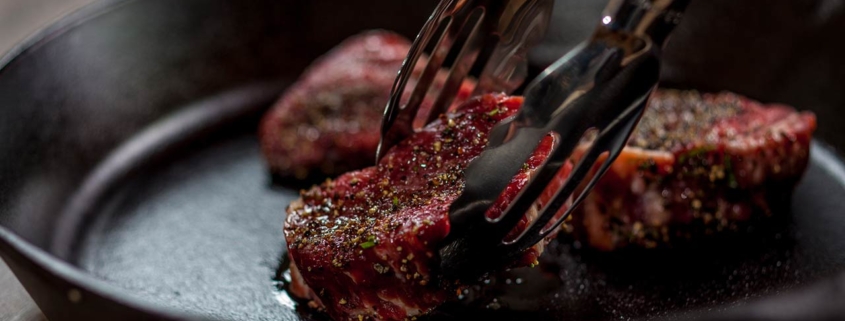 Chef is placing tenderloin steaks with kitchen tongs