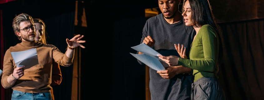 Theater director, multicultural actors and actress rehearsing on stage