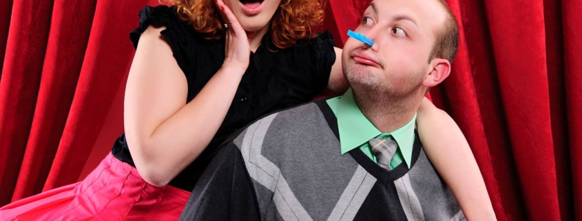 Torture of two lovers in front of a red theatre curtain