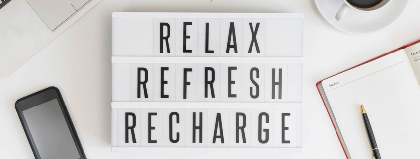 Relax, refresh and recharge words on office table with computer, coffee, notepad, smartphone and digital tablet