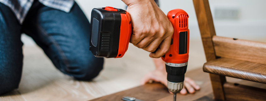 Man using hand drill to assemble a wooden table