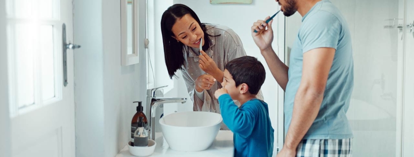 Parents, child and brushing teeth in bathroom while learning about dental hygiene