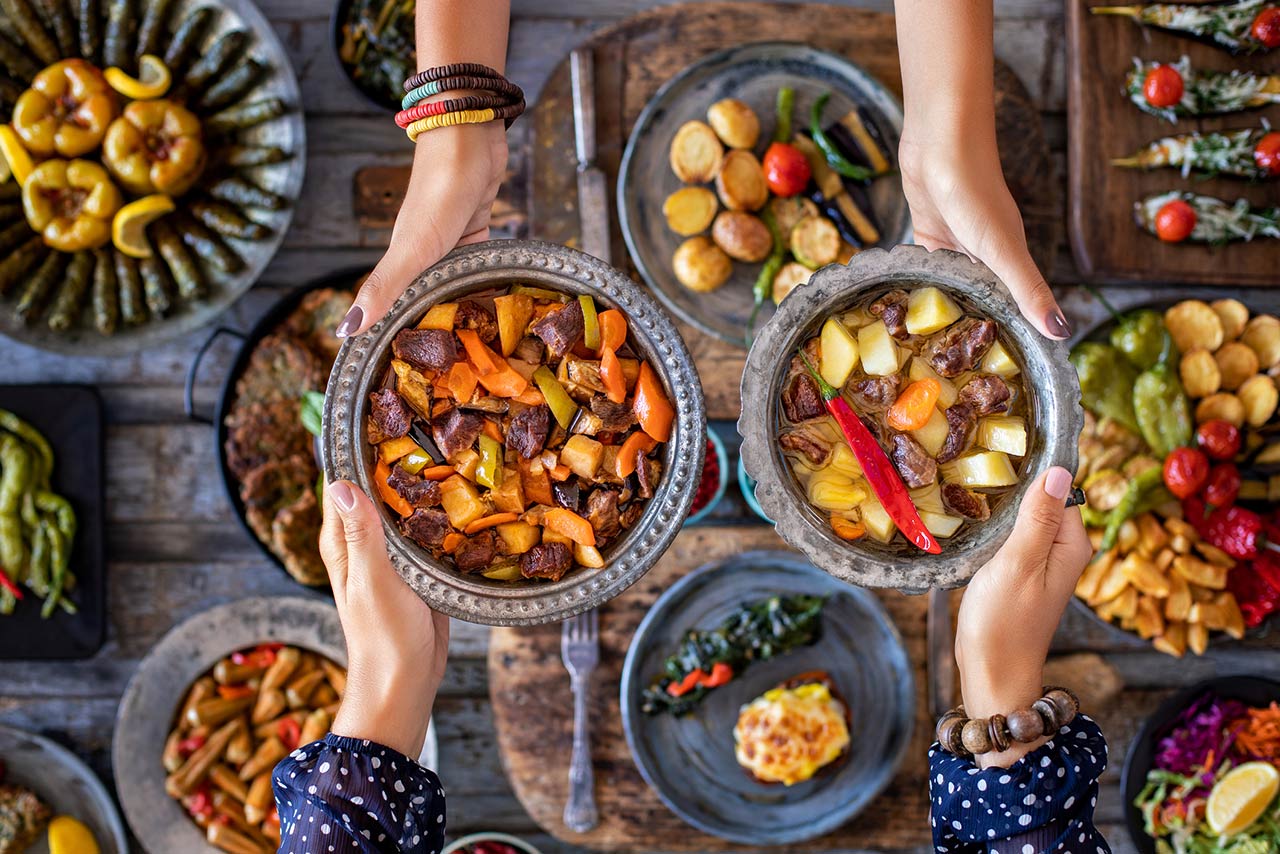 Female hands holding metal plates with meat stew with vegetables