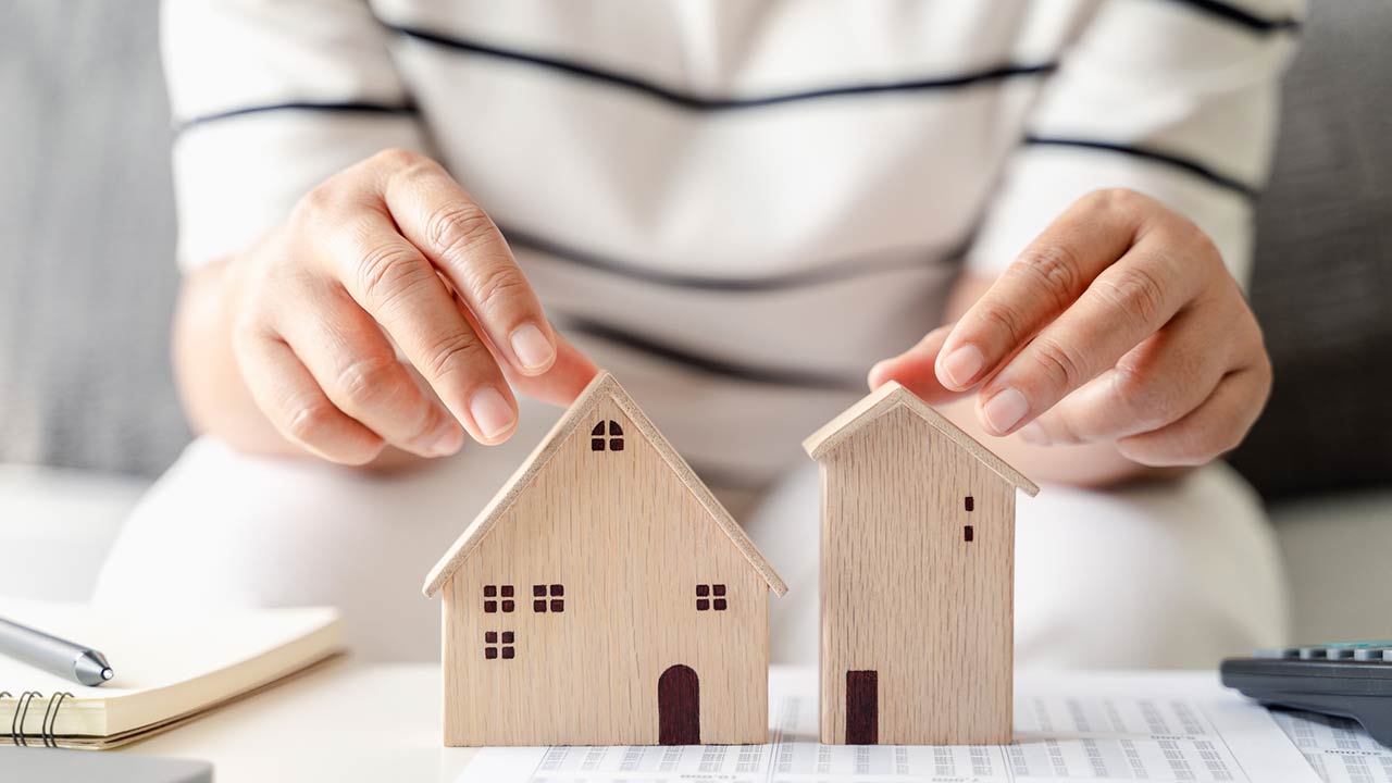 woman is deciding to choose house with Small Wooden House Model