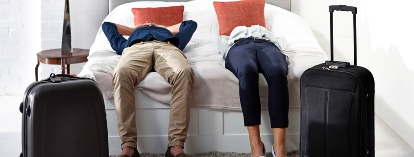 Indoor shot of mature couple lying on bed with luggage