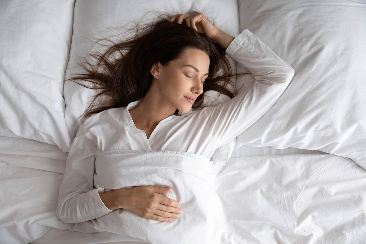 Peaceful serene beautiful young lady wear pajamas lying asleep relaxing sleeping in cozy white bed