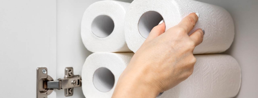 Womans hand taking out a roll of paper towel from the kitchen cabinet