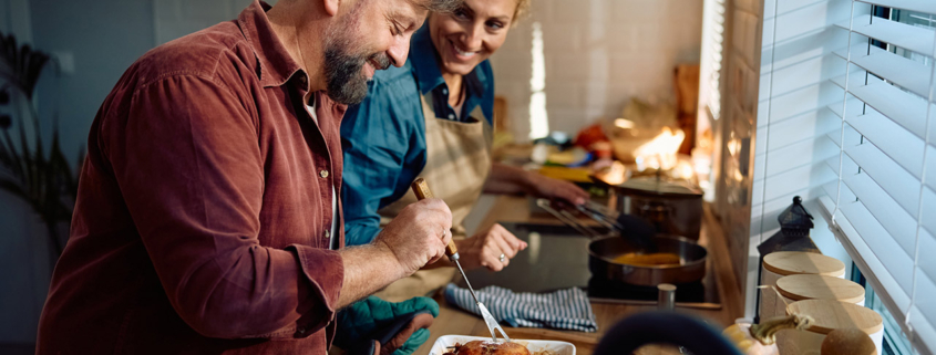 Happy couple preparing Thanksgiving turkey in the kitchen